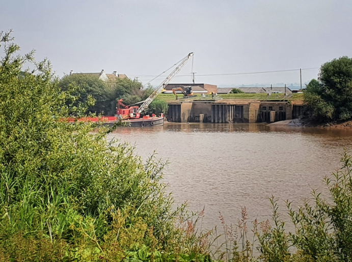 An image of contractors carrying out silt removal at the outfall.