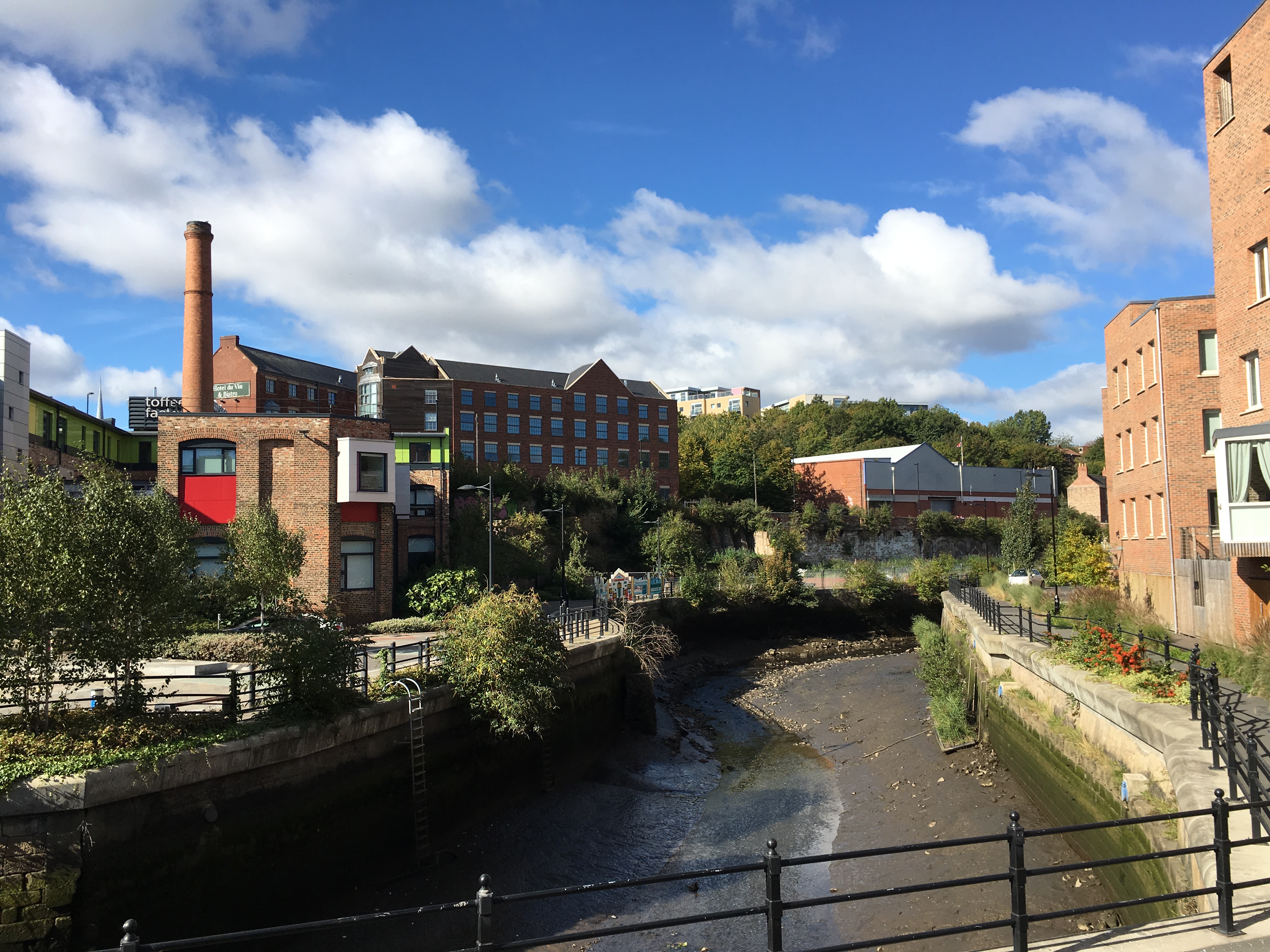 photo showing the lower Ouseburn flowing through an urban area with flats and old factory building