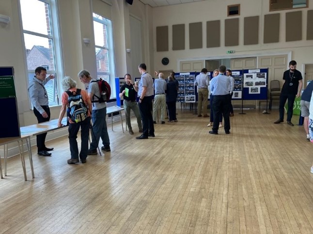 Picture shows a crowd of people looking at the drop-in displays and speaking with members of the project team