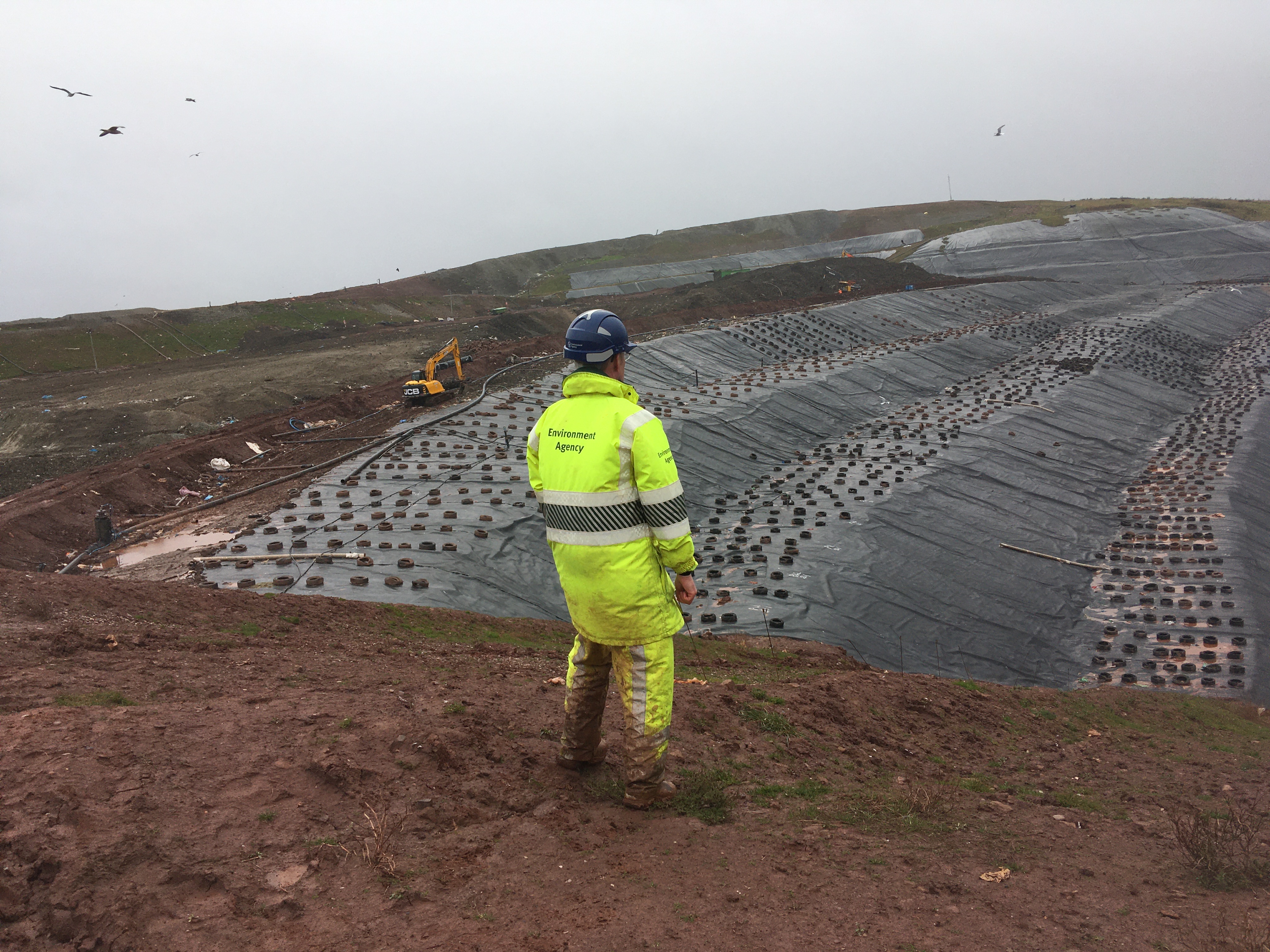 Photograph showing an Environment Agency Officer inspecting the temporary capping work on the slopes of the active tipping area.